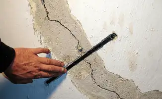 A wall with a large crack is being inspected by a professional in Hollywood, FL